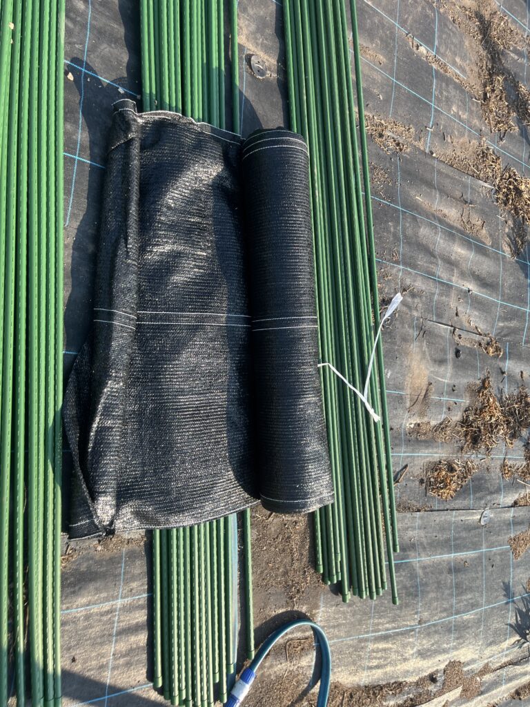 緑の棒と黒いシートが並べられた農業用の作業現場